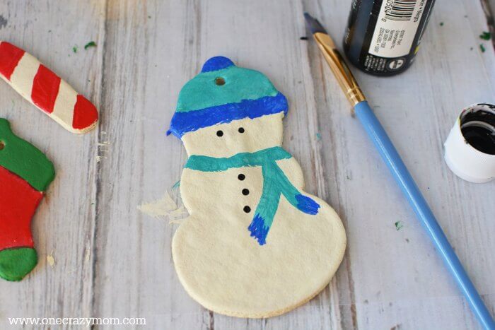 Make special memories with this simple and fun Salt Dough Ornament Recipe for Christmas. Learn how to make salt dough ornaments so easy the entire family can help! This great ornament DIY is perfect for kids. #onecrazymom #christmasornaments #DIYornaments #saltdoughornaments Snowman being painted.