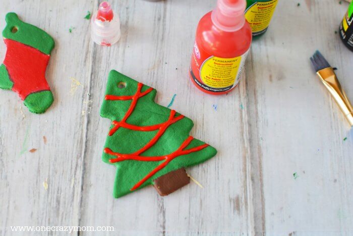 Make special memories with this simple and fun Salt Dough Ornament Recipe for Christmas. Learn how to make salt dough ornaments so easy the entire family can help! This great ornament DIY is perfect for kids. #onecrazymom #christmasornaments #DIYornaments #saltdoughornaments Christmas tree being painted.