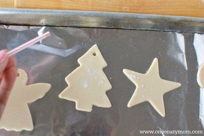 Make special memories with this simple and fun Salt Dough Ornament Recipe for Christmas. Learn how to make salt dough ornaments so easy the entire family can help! This great ornament DIY is perfect for kids. #onecrazymom #christmasornaments #DIYornaments #saltdoughornaments Ornaments on baking sheet.