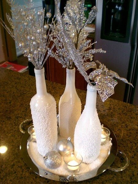 Create Christmas table top decorations with these easy ideas. 15 DIY Christmas table decorations anyone can make. Simple Christmas table decoration ideas. Wine bottles transformed into snowy vases.