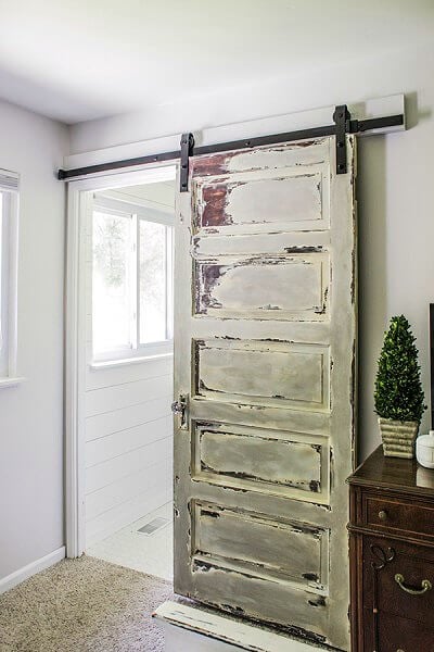 We have over 20 DIY Farmhouse decor ideas that are easy to make. Find lots of ideas that are budget friendly and simple to create for your home. Rustic barn door beside table.