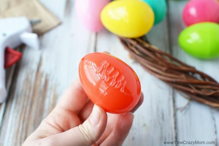 Make this DIY Easter Egg Wreath with items from the dollar store. You will love this easy Easter Egg Wreath DIY. Try this frugal Easter craft today. Glue on plastic egg.