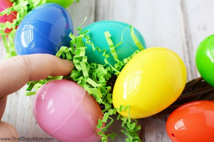 Make this DIY Easter Egg Wreath with items from the dollar store. You will love this easy Easter Egg Wreath DIY. Try this frugal Easter craft today. Filler being placed in between eggs.