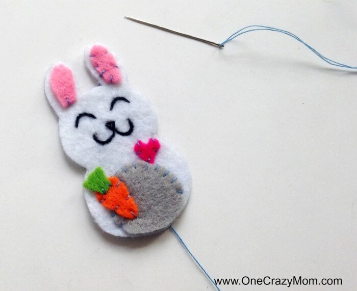 Easter felt crafts are so fun! Learn how to make a Bunny Charm. DIY Easter crafts are so simple. Kids will love this easy bunny craft! Find Easter craft ideas for kids. Easter crafts for kids they will love! Embellishments being sewn on charm.
