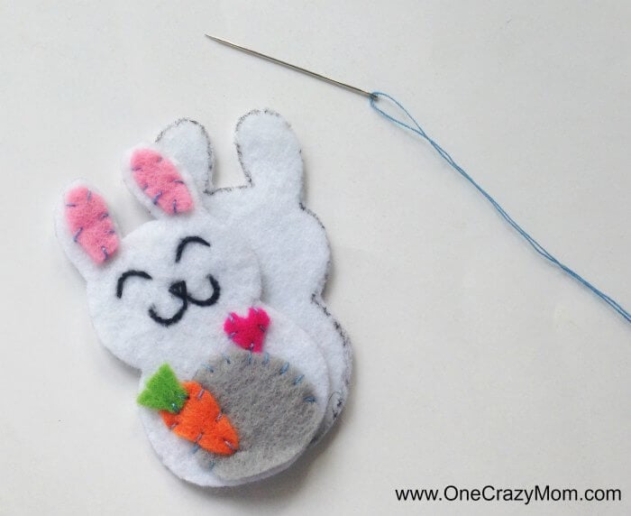 Easter felt crafts are so fun! Learn how to make a Bunny Charm. DIY Easter crafts are so simple. Kids will love this easy bunny craft! Find Easter craft ideas for kids. Easter crafts for kids they will love! Embellishments being sewn on charm.