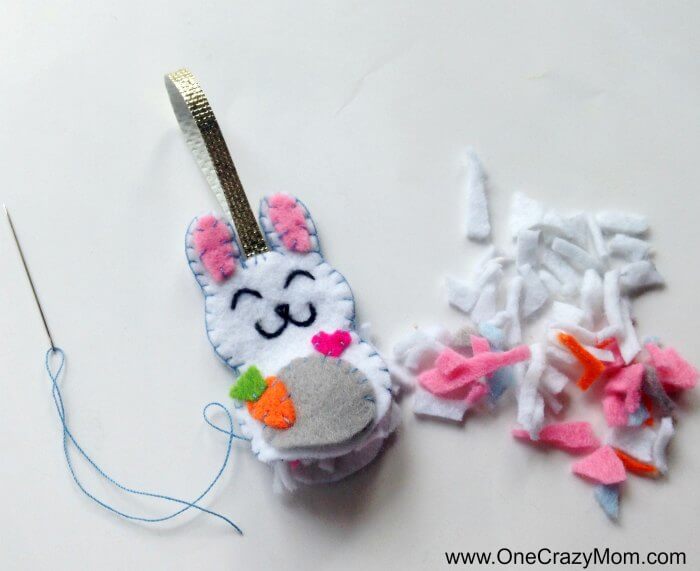Easter felt crafts are so fun! Learn how to make a Bunny Charm. DIY Easter crafts are so simple. Kids will love this easy bunny craft! Find Easter craft ideas for kids. Easter crafts for kids they will love! Bunny Charm with embellishments being sewn on.