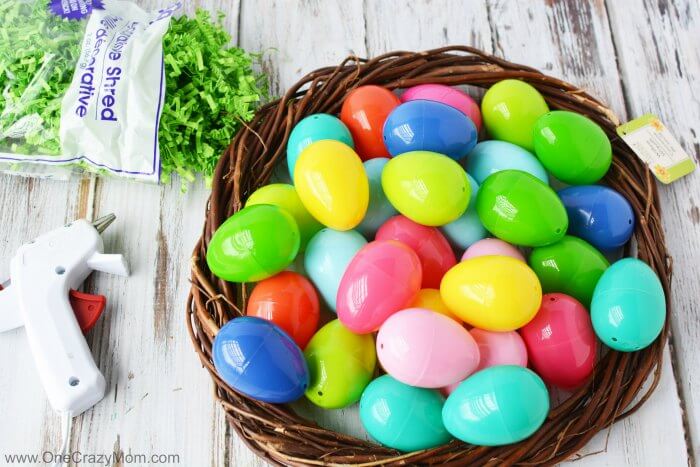 Make this DIY Easter Egg Wreath with items from the dollar store. You will love this easy Easter Egg Wreath DIY. Try this frugal Easter craft today. Plastic eggs in basket.