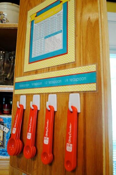 You will love these Dollar Store Kitchen Organization ideas! 20 Kitchen Organization hacks to get your kitchen in order for just a $1! You can't beat that! Measuring spoons hanging on the inner cabinet.