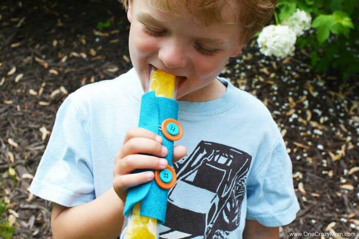 Learn how to make a DIY popsicle holder. It is so simple to make a homemade popsicle sleeve. Kid's will love having their very own popsicle holder. Little hands will not get cold using a homemade popsicle holder. They are so easy to make and budget friendly! Child eating popsicle.