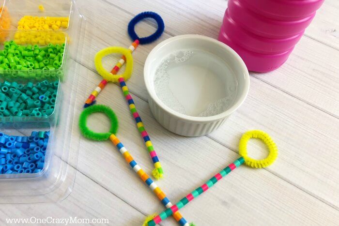 Learn how to make a bubble wand. Make this diy bubble wand for tons of fun. Homemade bubble wands are easy to make. Kids will love decorating the wands with beads. Wands beside solution and beads.