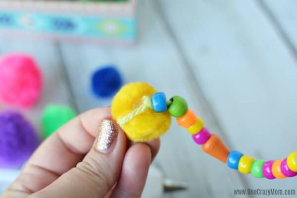 DIY wind chimes are really simple to make. Learn how to make wind chimes. It's so simple and easy. Everyone will have a blast making these pretty wind chimes. Attaching Pom Pom on string.
