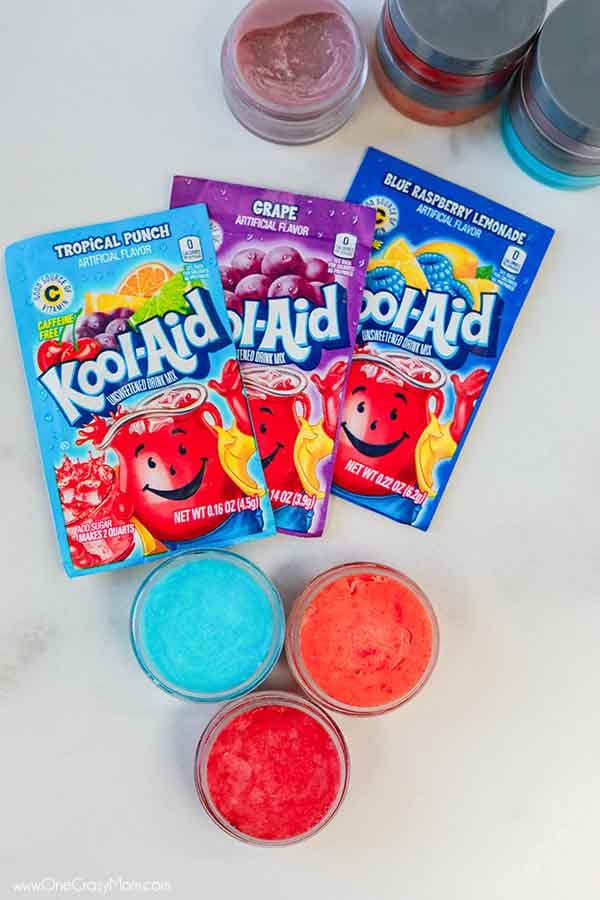 Koolaid lip gloss surrounded by packets of kool aid.