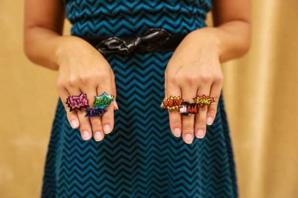 Everyone will have a blast making these 25 Shrinky Dink ideas that are easy to make. Find ideas from key chains and necklaces to magnets and much more! Person with shrinky dink rings on fingers.