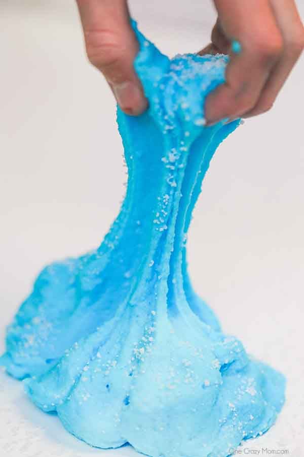 We have the best cloud slime recipe and it is super easy to make. If your kids love slime, they are going to love to learn how to make cloud slime. Blue cloud slime being pulled apart with a hand.