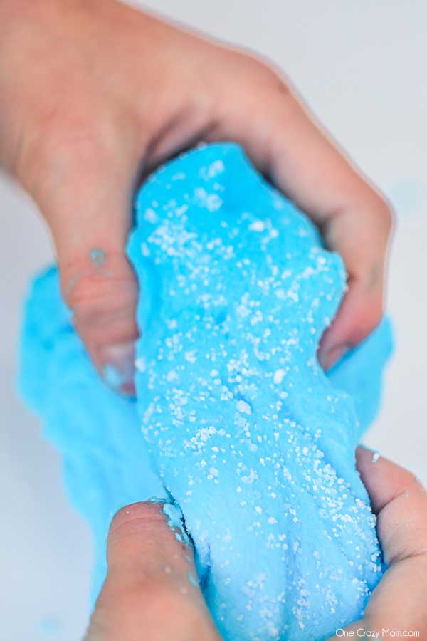 We have the best cloud slime recipe and it is super easy to make. If your kids love slime, they are going to love to learn how to make cloud slime. Hands pulling apart blue cloud slime.