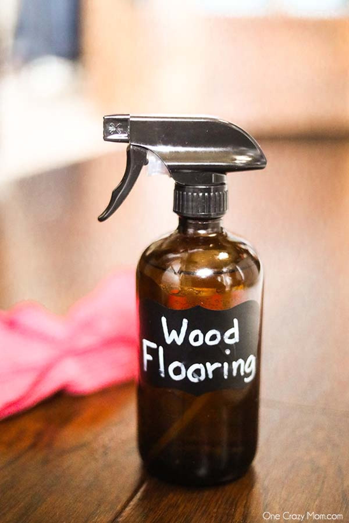 Make this DIY hardwood floor cleaner in just minutes for an all natural cleaner you will love. From floors to trim and more, your wood will be so clean. Glass Spray Bottle with homemade cleaner on hardwood floors with a Microfiber cloth