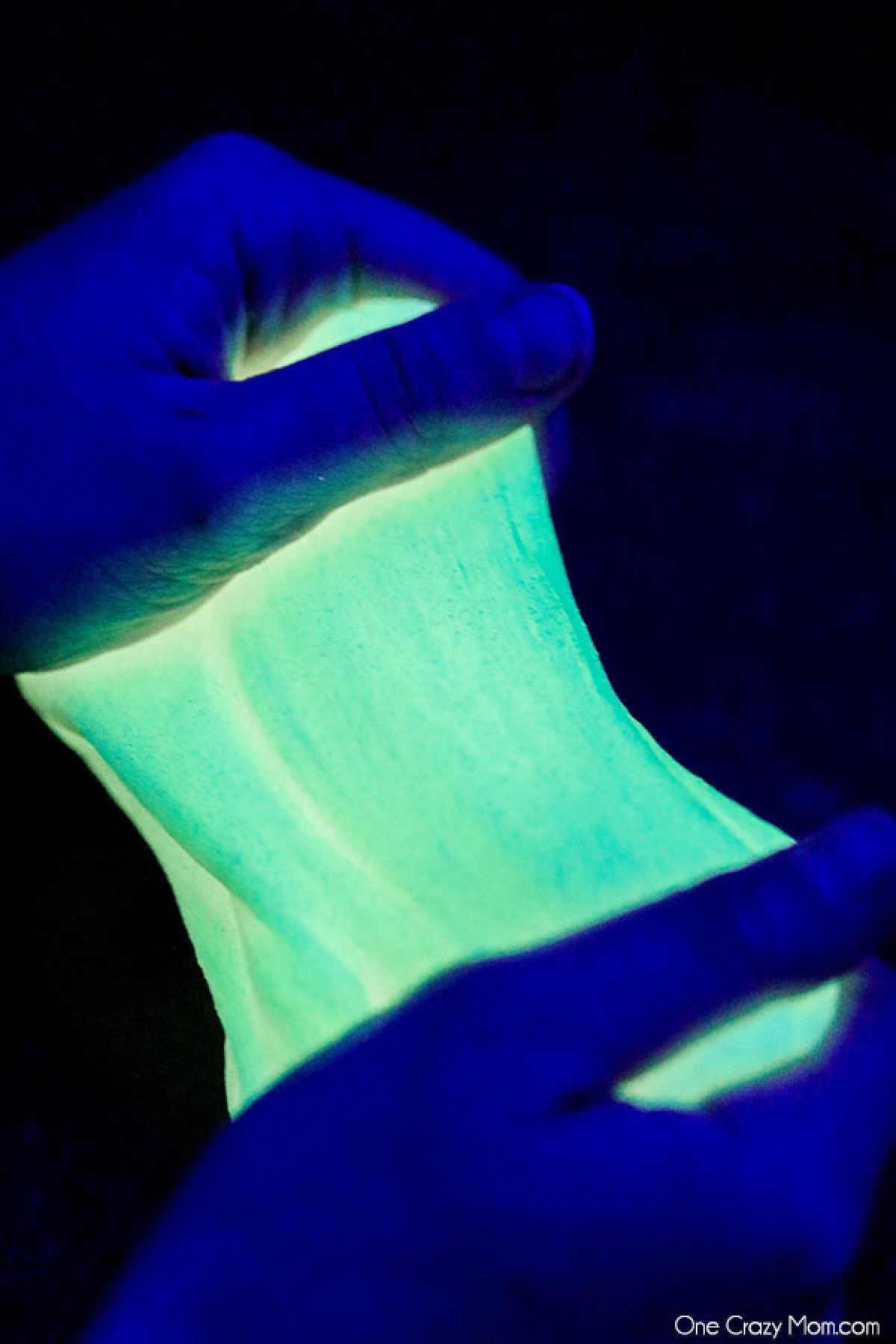 Glow in the dark slime takes slime to a new level and everyone will love this fun DIY. Learn how to make glow in the dark slime with only 3 ingredients. Glow in the dark slime being stretched out.