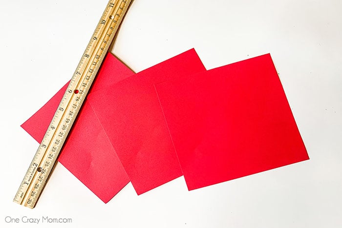 Learn how to make an Origami Heart with these easy step by step instructions. This is such a simple DIY but tons of fun and a great activity for the kids. 3 Red pieces of square paper with a ruler
