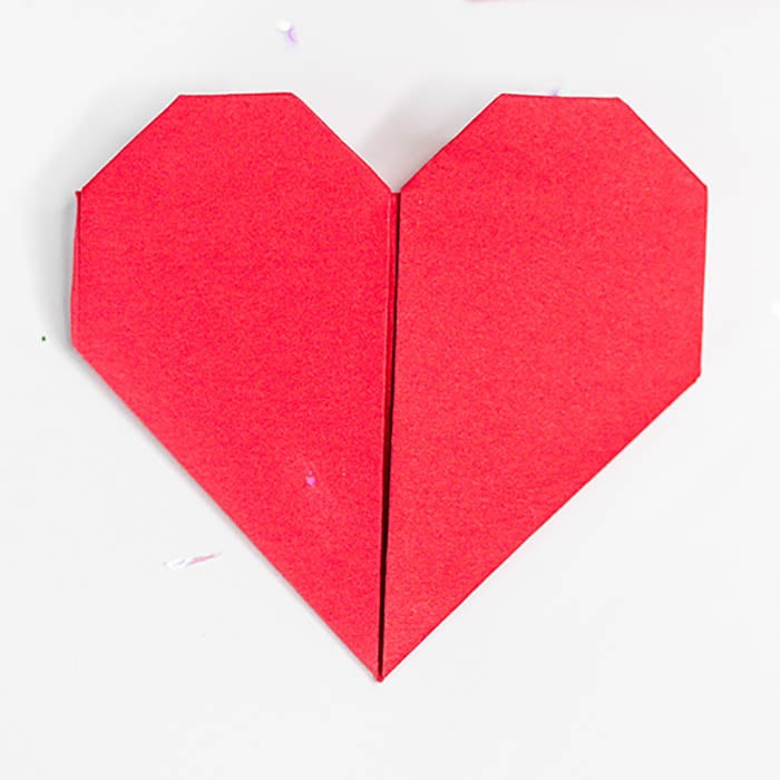 Learn how to make an Origami Heart with these easy step by step instructions. This is such a simple DIY but tons of fun and a great activity for the kids. Close up of a red origami heart