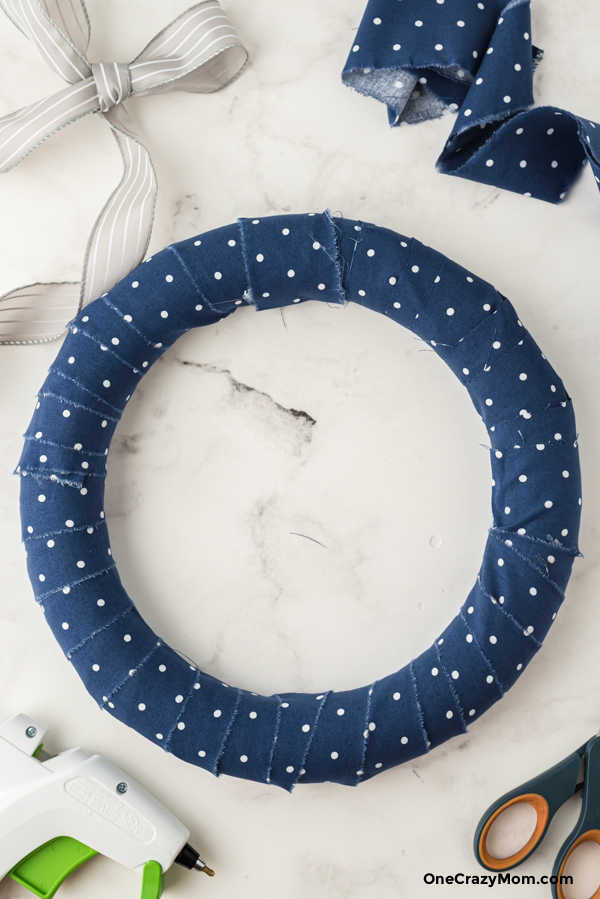 Wrapping strips of fabric on wreath.