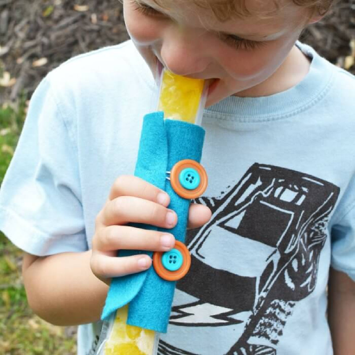 Learn how to make a DIY popsicle holder. It is so simple to make a homemade popsicle sleeve. Kid's will love having their very own popsicle holder. Little hands will not get cold using a homemade popsicle holder. They are so easy to make and budget friendly! Child holding popsicle in holder.