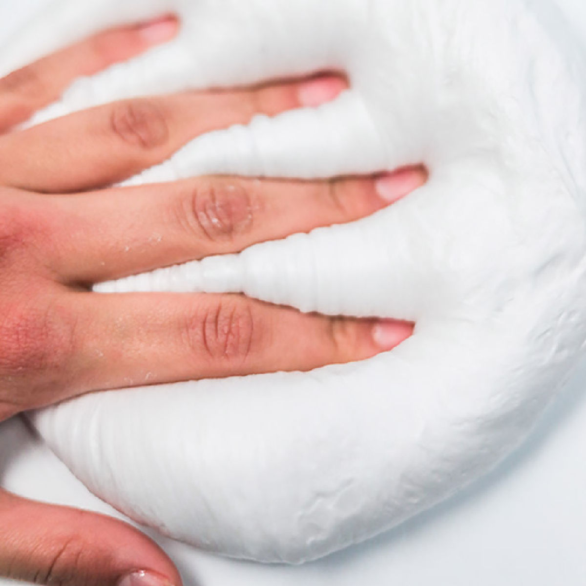 Snow Slime is so fun to make and only requires a few supplies. This is super easy and the kids will go crazy over this snow slime recipe. Pile of snow slime with hand on top.