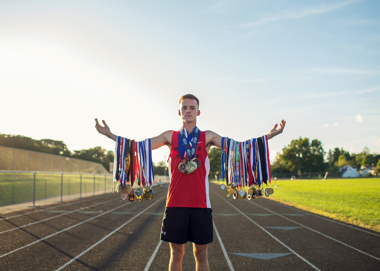 Track runner with medals on arms.