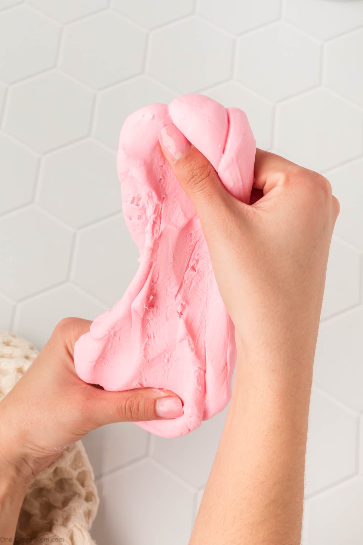 Cornstarch slime in hands being stretched.